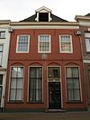 Huis met lijstgevel met gepleisterde pui, gevelsteen en dakkapel