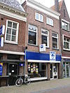 Pand met lijstgevel en jongere winkelpui en met restanten van de middeleeuwse stadsmuur