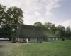 Overzicht van de linkerzijgevel met de deel van de boerderij met rieten dak