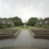 Overzicht van het voorplein met de twee bouwhuizen en de toegangslaan, gezien vanaf de entree van het kasteel