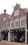 Huis met ingezwenkte halsgevel met omlijste geveltop, ramen met geprofileerde bovendorpels en gewijzigde onderpui