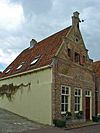 Huis met bakstenen puntgevel met waterlijsten en uitgekraagde toppilaster met sieranker