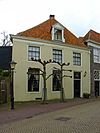 Diep ten dele vrijstaand huis met gepleisterde buitenmuren en verdieping on der schilddak