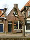Huis met gepleisterd puntgeveltje met uitgekraagde toppilaster