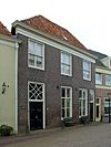 Huis met bakstenen gevel met rechte kroonlijst, empire-schuiframen en eenvoudig bovenlicht