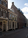 Pand met lijstgevel met dakkapel, gepleisterde raam- en deuromlijstingen met versierde boogbeeindigingen en gepleisterde plint met panelen