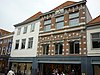 Brede lijstgevel waarachter huis van oudere datum