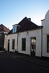 Huis met bakstenen lage gevel met rechte kroonlijst. Vormt een geheel met nr 43