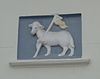 Huis met gepleisterde eenvoudige lage lijstgevel. Gevelsteen met 't Lam Gods. Een geheel met nr 12