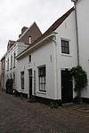 Laag eenvoudig gepleisterd huis, uitspringend naast nr 35b