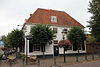 Huis met eenvoudige gewitte bakstenen topgevel. Vensters met 18e-eeuwse roedenverdeling. Vroegere stadsherberg