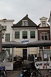 Huis met eenvoudige gepleisterde lijstgevel met gebeeldhouwde satirekop