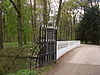Detail BRUG met PIJLERS en HEKKEN.JPG -  Ten noordwesten van het hoofdgebouw wordt de oprijlaan over de Kromme Rijn geleid via een houten brug met wit geschilderde decoratieve gietijzeren brugleuningen. De vormgeving van de brug gaat terug tot circa 1860. In de Tweede Wereldoorlog werd de brug door de Duitsers opgeblazen. Na de oorlog werd hij hersteld. Aan de kant van het huis wordt het bruggenhoofd gemarkeerd door een stel hardstenen pijlers op rechthoekige grondslag, waarvan de hoeken afgeschuind zijn. De pijlers zijn horizontaal …