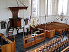 Wilnis, Koningin Julianastraat 23, NH kerk, liturgisch centrum - img2174 -  Liturgisch centrum van de kerk. Zichtbaar zijn de twee doopbogen en de lezenaar. Deze zijn afkomstig uit de oude kerk (die in 1876 instortte). Tevens een deel van de kansel en twee kaarsenkronen. 