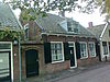Dwarshuis onder hoog pannen zadeldak tussen puntgevels met vlechtingen