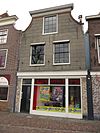 Pand met schilddak, gepleisterde gevel met ingezwenkte zijkanten en houten kroonlijst