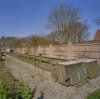 Overzicht gerestaureerde koude kweekbak en tuinmuur, met stapels broeiramen