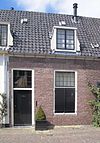 Pand met gepleisterde lage gevel met rechte kroonlijst