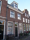 Dubbel pand met brede klokgevel, aan de top boogstuk met wapensteen