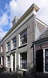 Breed herenhuis met rechte kroonlijst, brede ramen, hekkettingen, overtuintje, geschoren linden