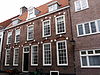 Pand met brede rechte lijstgevel, bogen met natuurstenen blokken boven de vensters, stenen gemetselde gootlijst
