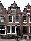 Pand met dubbele trapgevel met natuurstenen blokken in bogen en sierankers, 1e helft