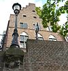 Drakenburg te stad Utrecht incluis werfmuur en bijbehorende lantaarnconsole -  Stadskasteel Drakenburg p/a Oudegracht te stad Utrecht. Op de voorgrond de werfmuur met een lantaarnconsole met een uitbeelding van Drakenburg, vervaardigd door Jeanot BÃ¼rgi, circa 1970? 