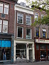 Huis, met een gevel uit circa 1850, met drie bouwlagen, een zadeldak loodrecht op de straat en kelders