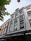 Pand met een 19e-eeuwse gevel, tegenwoordig bestaande uit drie bouwlagen, een kap loodrecht op de straat, een kelder en een werfkelder