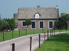 Boerderij op T-vormig grondplan bakstenen gebouw met woongedeelte onder rieten zadeldak tussen zijtopgevels met vlechtingen en het bedrijfsgedeelte onder afgewolfd rieten zadeldak