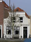 Huis met geverfde ingezwenkte lijstgevel. Staafankers. Voordeuromlijsting