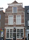 Huis de Baerse. Pand met geverfde ingezwenkte lijstgevel, de lijst met gesneden consoles. Muurankers, natuurstenen banden en waterlijst