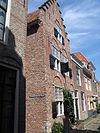 Pand met verticaal lessenaarsdak langszij aan de straat, gecombineerd met naastliggend pand met trapgevel