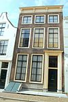 Huis met lijstgevel op plint van natuursteen met zwart geschilderde banden