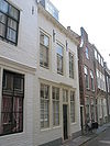 Huis met geverfde rechte gevel, gootlijst op klossen