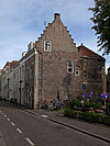 Hoekhuis met gepleisterde lijstgevel en aan de zijde van de vismarkt vernieuwde zijtrapgevel