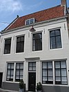 Huis met brede gecementeerde rechte gevel en zijtopgevel met vlechtingen