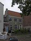 Apart genummerde ingang in gepleisterde zijgevel van het pand Korte Noordstraat 2