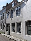 Huis met geverfde rechte gevel met gootlijst op klossen