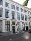 Huis met gepleisterde lijstgevel op plint van natuursteen met zwartgeschilderde banden