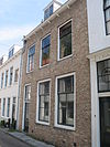 Huis met rechte gecementeerde gevel, op klossen rustende gootlijst
