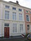 Pand met in blokken gepleisterde lijstgevel met stucwerk opgesierd