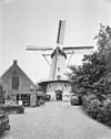 Witte ronde stenen stellingmolen van voren gefotografeerd met links het restaurant 'De Pannekoekenmolen' - Burgh-Haamstede - 20352307 - RCE -  De Graanhalm/ De Graanhalm: Witte ronde stenen stellingmolen van voren gefotografeerd met links het restaurant 'De Pannekoekenmolen' (opmerking: Gefotografeerd voor Monumenten In Nederland Zeeland) 