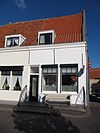 Huis met gepleisterde langsgevel in blokken gevoegd
