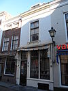 Huis met gepleisterde lijstgevel. Winkelpui