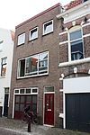 Huis met 19e-eeuwse bepleisterde lijstgevel. Fraaie kap. Nok evenwijdig aan de straat. Dakkapel. Getoogde vensters