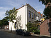 Gepleisterd hoekpand, bestaande uit parterre, verdieping en schilddak. Vensters met geprofileerde omlijstingen en kuiven van stucwerk. Kroonlijst met in het fries spiegels en consoles
