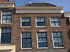 Huis met eenvoudige 19e-eeuwse lijstgevel. Schilddak. Moderne winkelpui