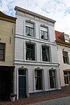 Huis met derde kwart 19e eeuw gepleisterde lijstgevel. Het fries van de lijst voorzien van panelen en consoles. Moderne winkelpui