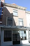 Huis met tweede helft 19e eeuw gepleisterde lijstgevel. Moderne winkelpui
